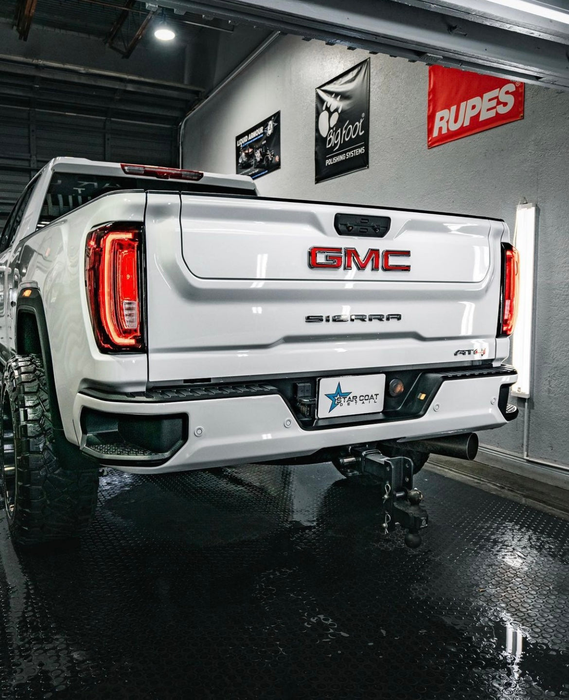 White GMC pickup in a detailing studio with a custom plate cover