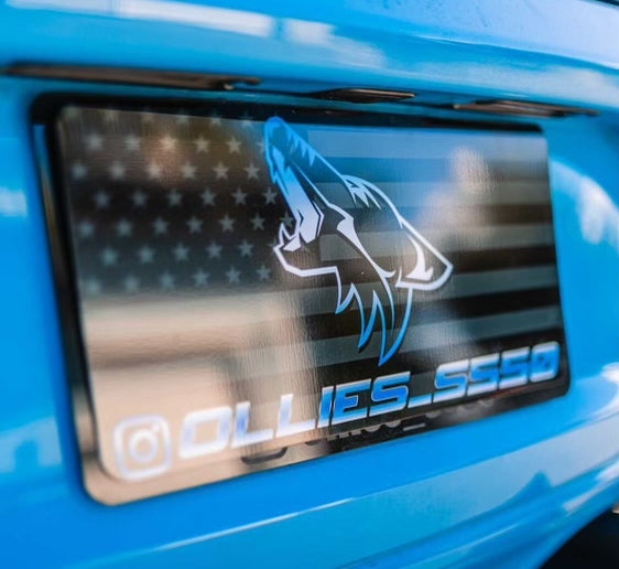 Close-up of a Coyote flag plate cover on a blue Mustang