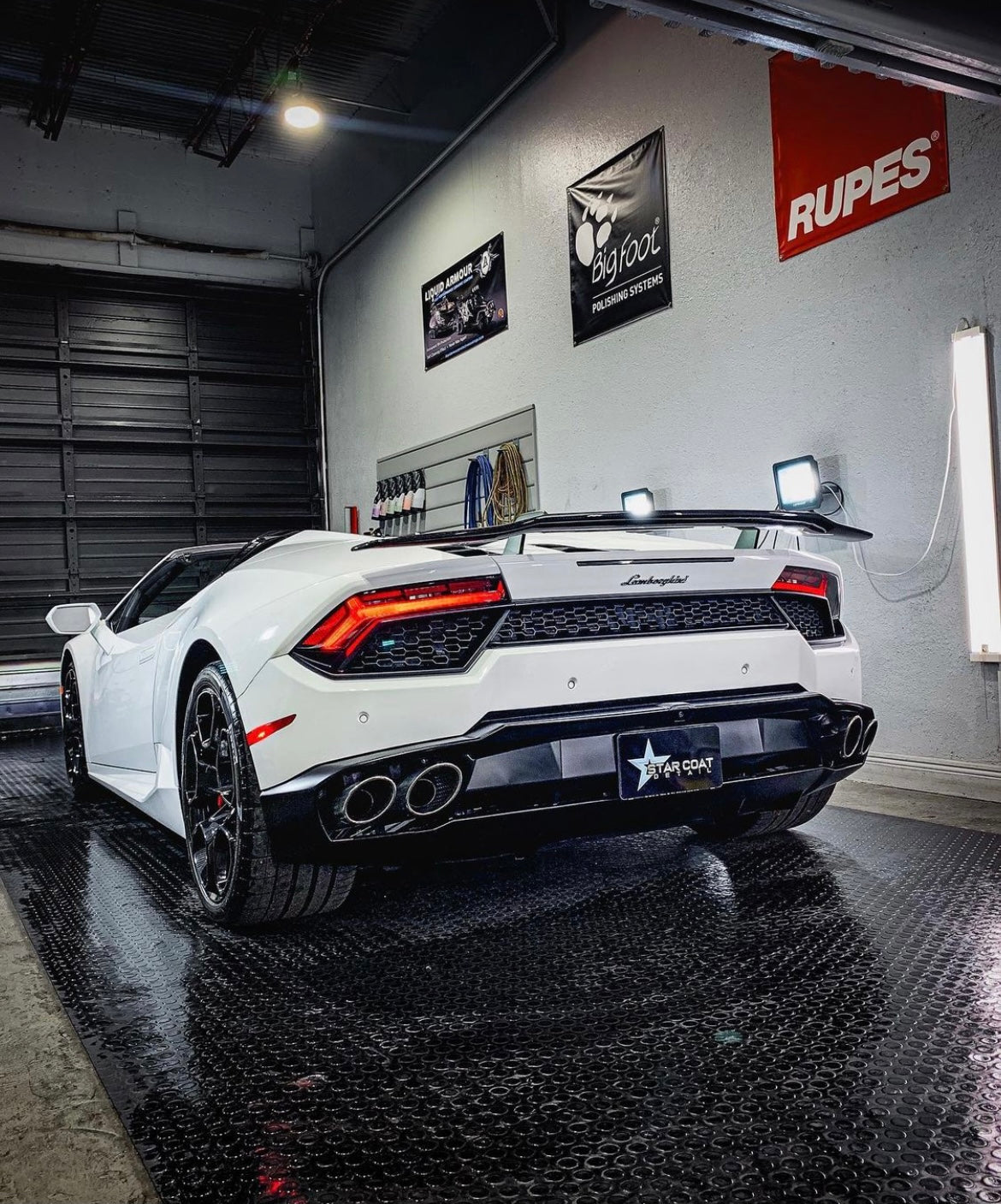 White Lamborghini in a detailing studio with a custom plate cover