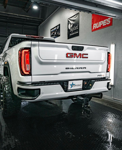White GMC pickup in a detailing studio with a custom plate cover
