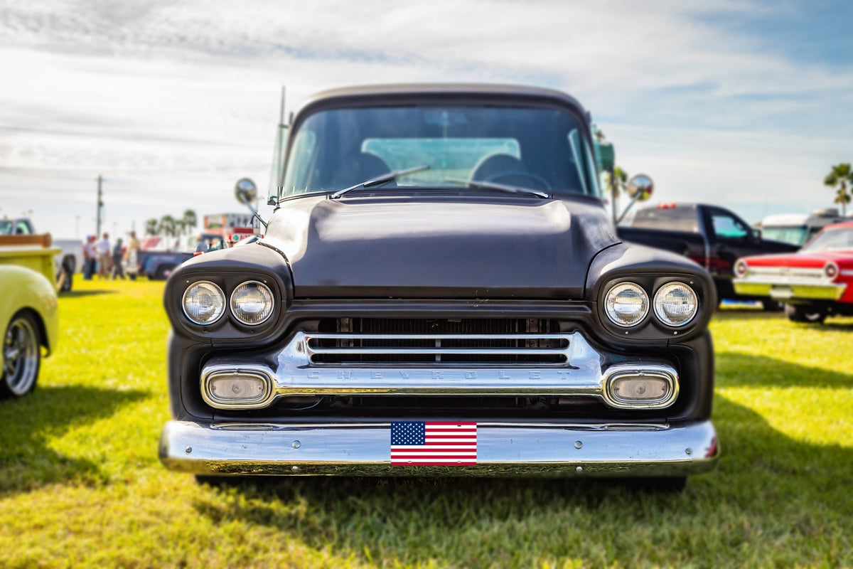 Classic Chevy pickup at a car show with an American flag front plate