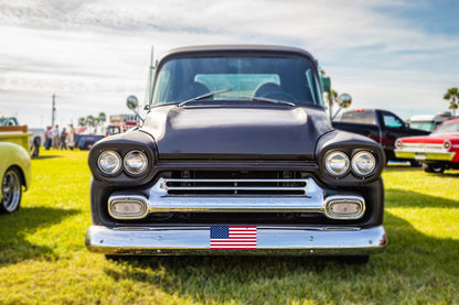 Classic Chevy pickup at a car show with an American flag front plate