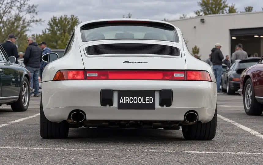 White Porsche 911 at a car meet with a custom plate cover