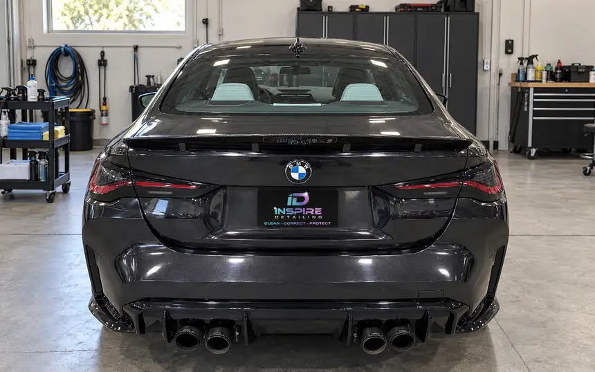 BMW M4 in a detail shop with the shop logo on a plate cover